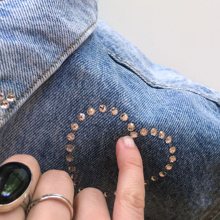 close up crystals on denim jacket with hand