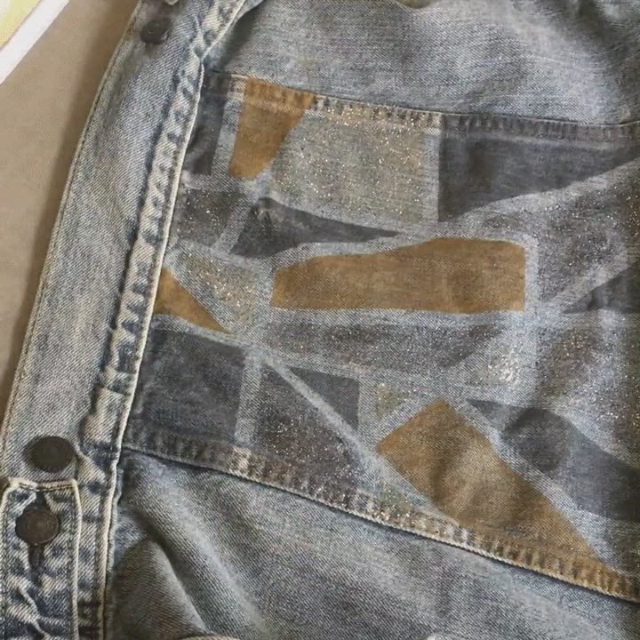 Video of thin yellow tape being removed from the back of a trucker jacket and the Levi's® tailor ironing the newly painted design with a layer of cloth to protect and lock in the design.