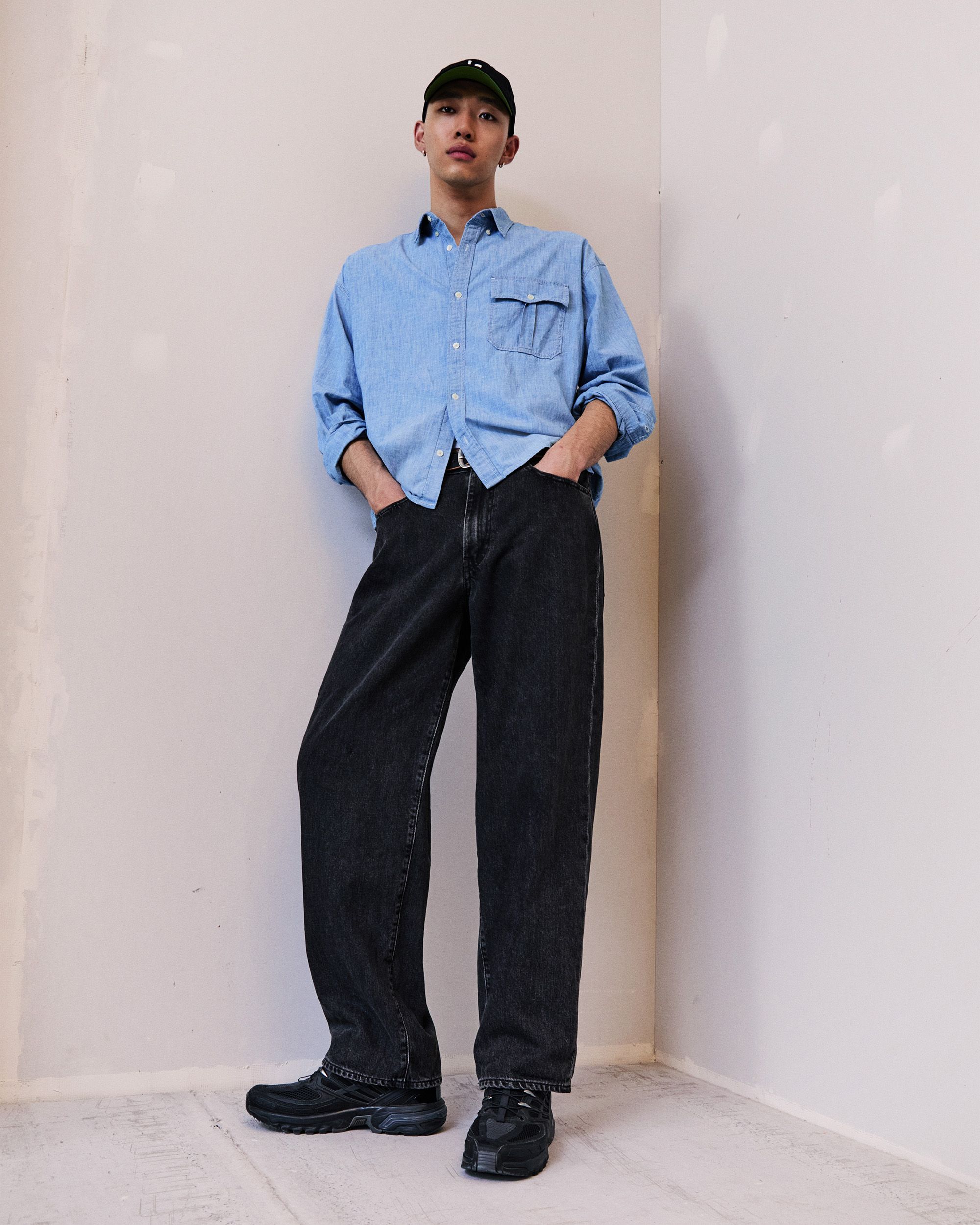 Model in blue button up and green/blue sweater over the shoulders