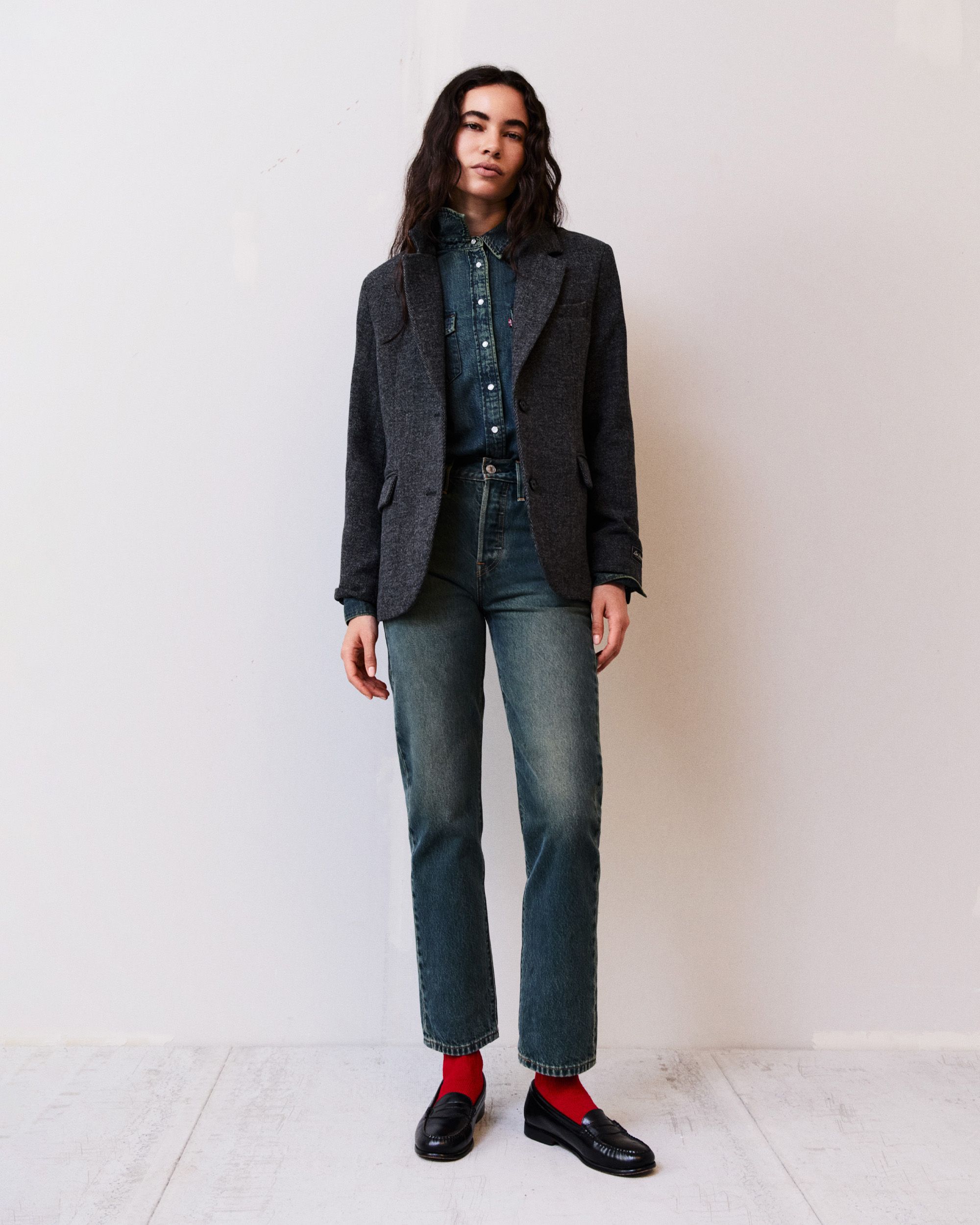 Model in denim button up, dark wash jeans, and dark wash blazer