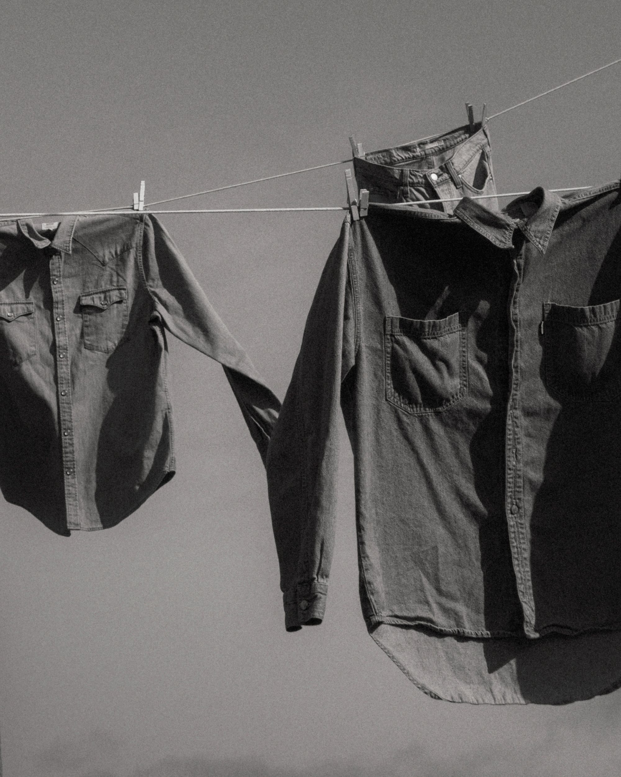 Black & white image of men's denim shirts on clothes line