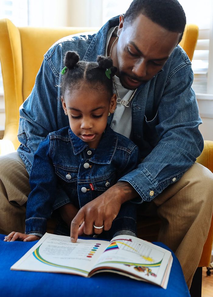 Photo of Adrian Walker reading to his daughter Emory. They are both wearing Levi's Trucker Jackets.