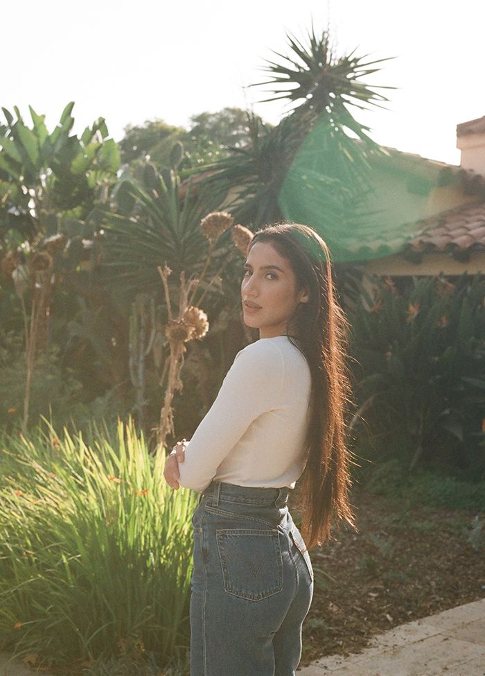 Portrait of ABIR standing outside in a white long-sleeve shirt and Levi's jeans.