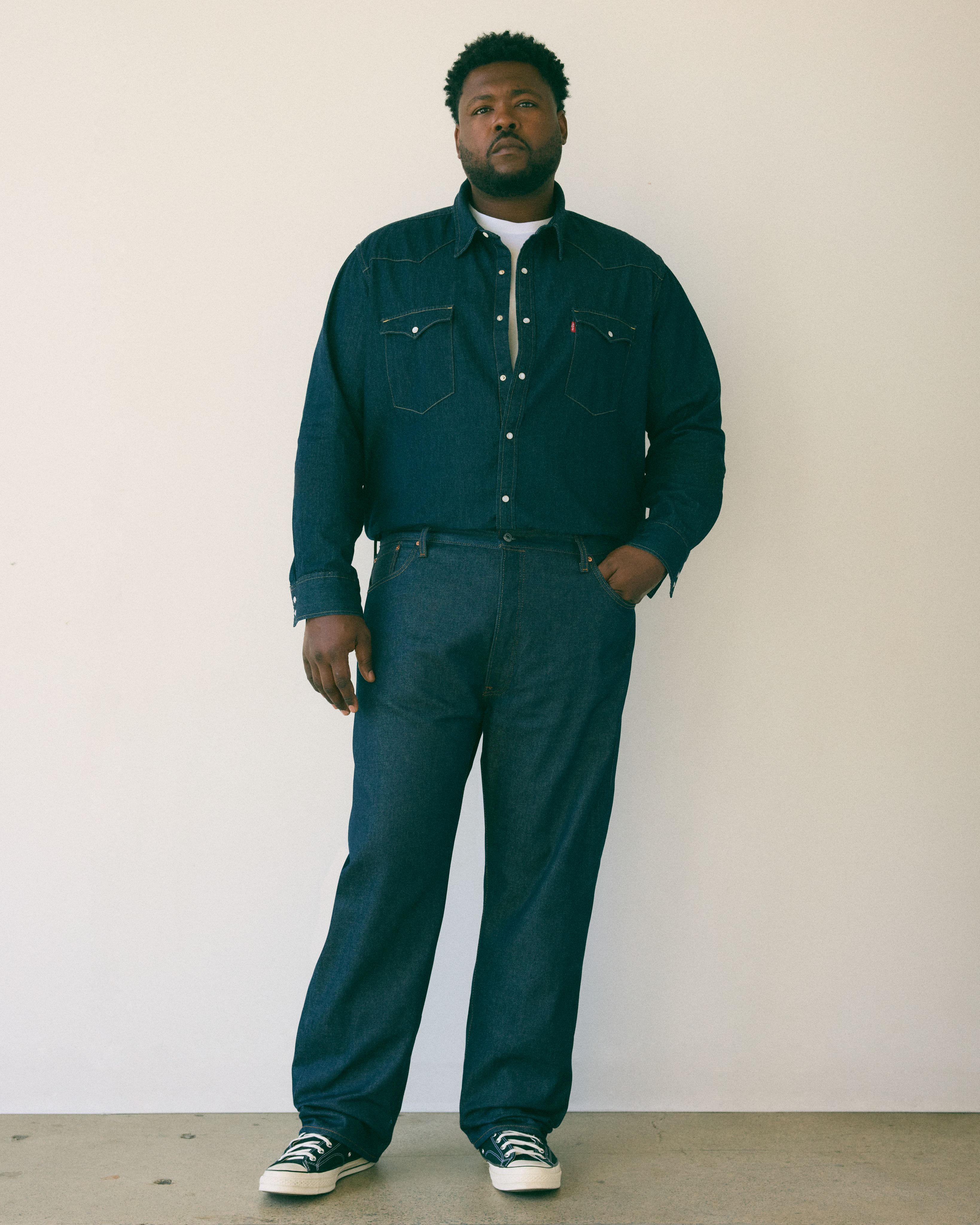 Big & tall male model wearing jean pants and a tee.