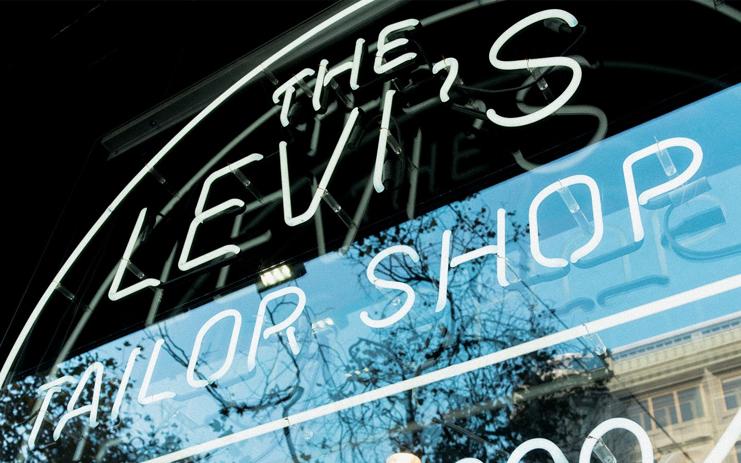 The window of a Levi's tailor shop with an electric sign saying, "The Levi's Tailor Shop"