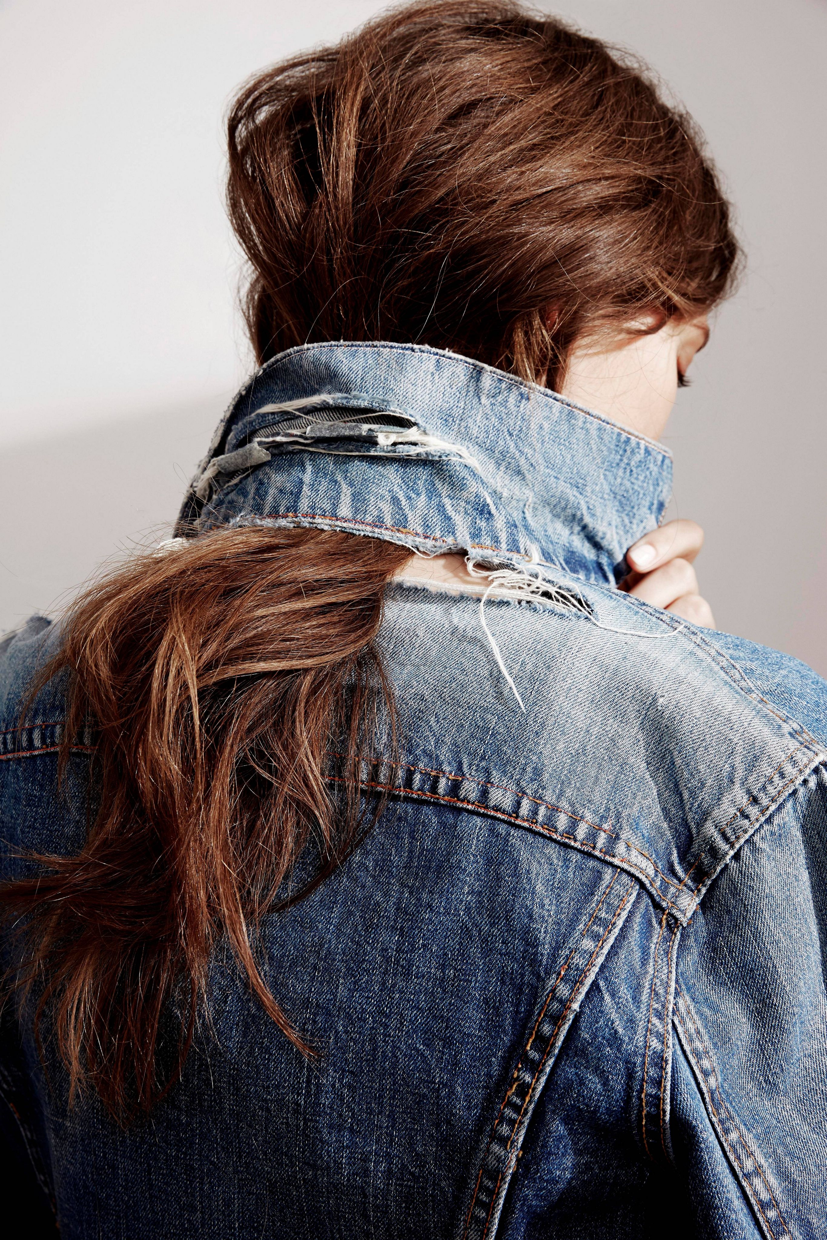 denim jacket. women's hair caught through the back