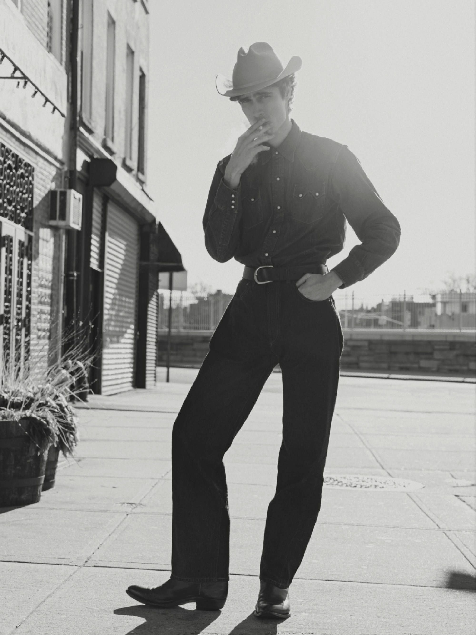 black and white image of man standing in cowboy boots.
